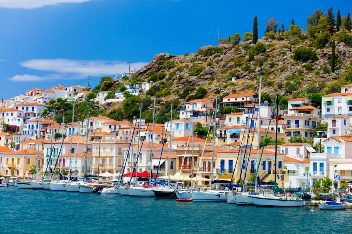 Vibrant hillside homes and docked sailboats on Poros Island.